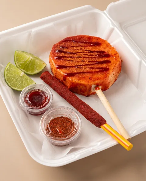 A red chamoy jicaleta with coconut and chili dips