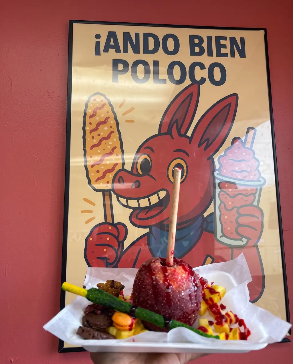 The Poloco poster of the red burro, with a chamoy-covered apple on a tray in front of it