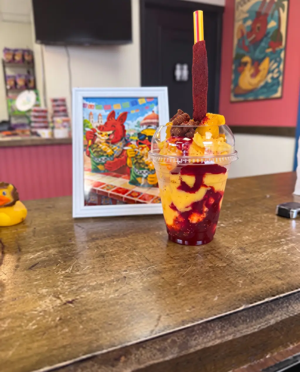 A Poloco parfait on the table in front of the shop's framed burro artwork, with a yellow rubber duck beside it